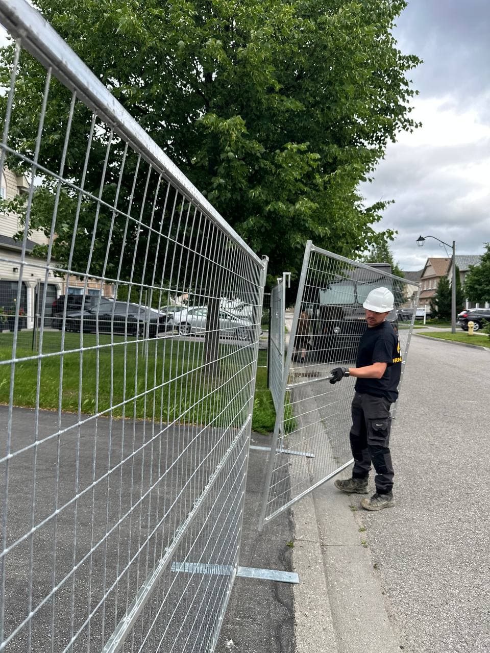 Orna Fence technician installing a long run of temporary fence panels to secure a site in Durham Region